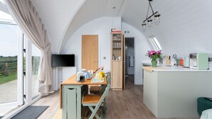 Une cuisine moderne avec un coin repas, un téléviseur et une vue sur l’extérieur.