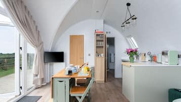 Eine moderne Küche mit Essbereich, einem Fernseher und Blick ins Freie.