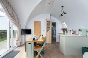 A modern kitchen with a dining area, a television, and a view of the outdoors.