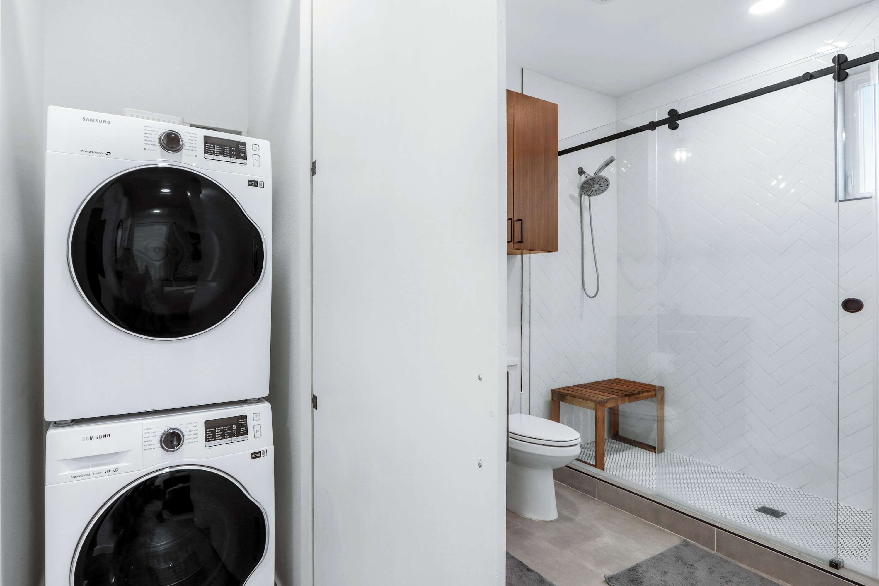 Ein modernes Badezimmer mit Duschkabine aus Glas, Toilette und einer hölzernen Sitzbank.