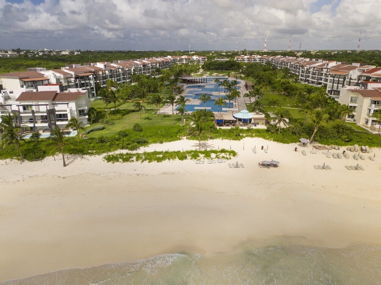 Um resort com vários edifícios, piscina e área de praia.