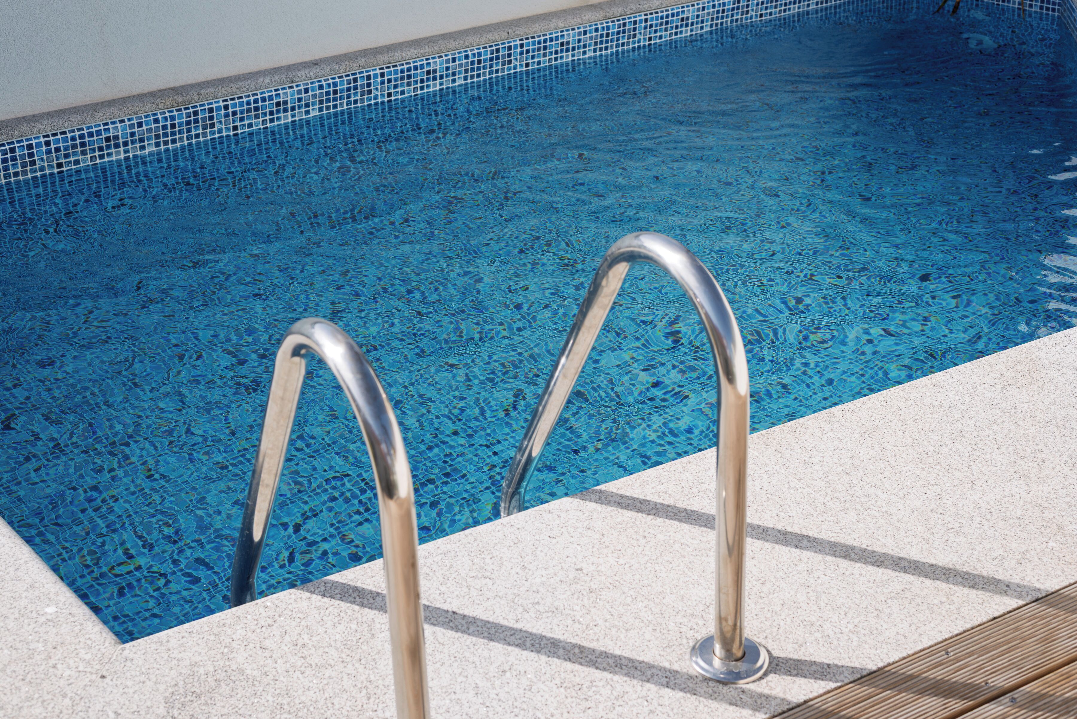 A swimming pool with clear blue water and metal pool ladders.