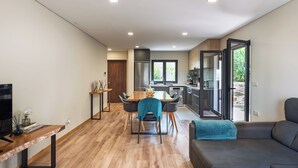 A modern kitchen with a dining area, a sofa, and a TV.