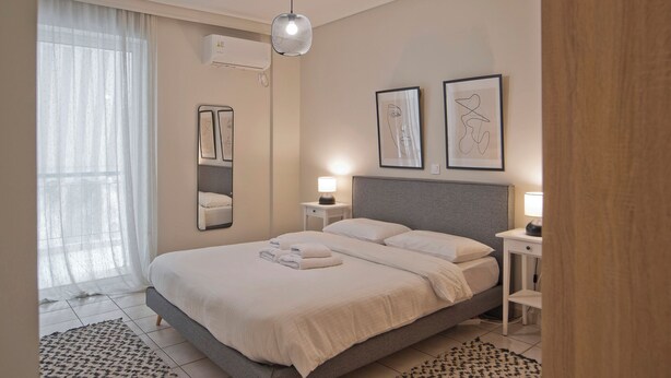 A modern bedroom with a large bed, bedside lamps, a mirror, and abstract art on the wall.
