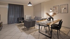 A modern living room with a sofa, a dining table with chairs, a coffee table, and a pendant light.