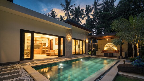 A modern house with a swimming pool, large windows, and a well-lit interior.