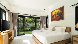 A modern bedroom with a large bed, a television, and a sliding glass door leading to a garden.
