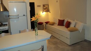 A compact kitchen with a refrigerator, stove, and a dining area with a table and chairs. - Apart Avenida (Concordia)