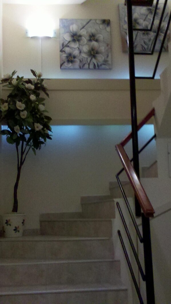 A staircase with a wooden handrail and a potted plant on the left. - Apart Avenida (Concordia)