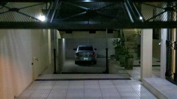 A car parked in a covered driveway with a tiled floor and a metal roof. - Apart Avenida (Concordia)