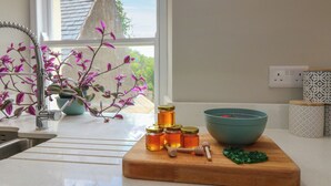 A kitchen counter with a cutting board, honey jars, a bowl, and a potted plant. - Ashlea (Lauder)