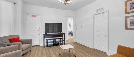 A modern living room with a flat-screen TV, two sofas, a coffee table, and a ceiling fan.