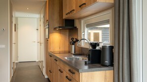 Una cocina moderna con armarios de madera, un lavamanos de acero inoxidable y una cafetera.