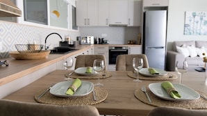 A dining area with a wooden table set for four, including plates, cutlery, and wine glasses.