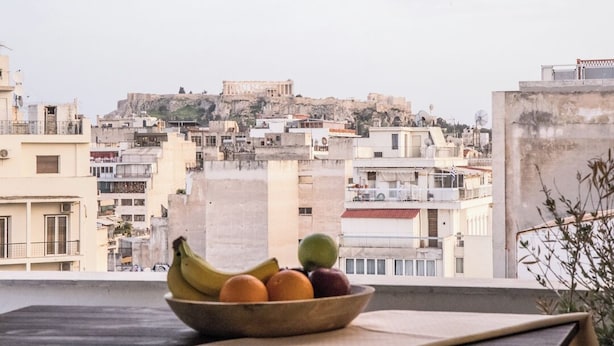 A bowl of fruit on a balcony with a view of a historic cityscape.