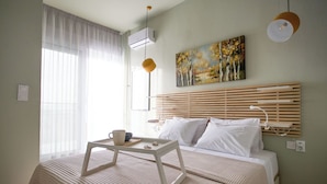 A bedroom with a bed, bedside table, and a painting on the wall.