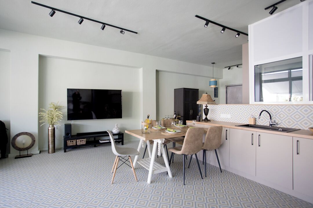A modern kitchen with a dining area, featuring a large flat-screen TV, a dining table set for four, and a built-in oven.