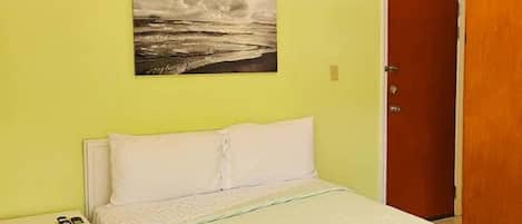 A bedroom with a bed, a nightstand, a door, and a painting on the wall.
