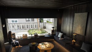 A modern living room with a large window, a round coffee table, a sofa, and a speaker.