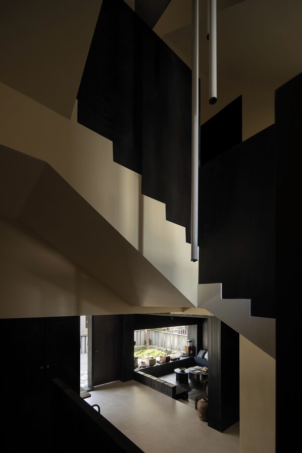 Un interior moderno con una escalera que conduce a un nivel superior. Hay una zona de estar con un sofá y una mesa de centro en el nivel inferior.