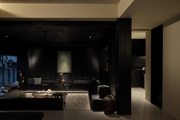 A modern living room with a dark color scheme, a sofa, a coffee table, and a large vase. - PlayHome-Seeing the Soul's Retreat (Hangzhou)
