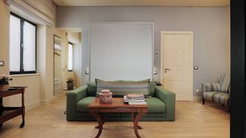 Un salon avec un canapé vert, une table basse en bois et un fauteuil à rayures.