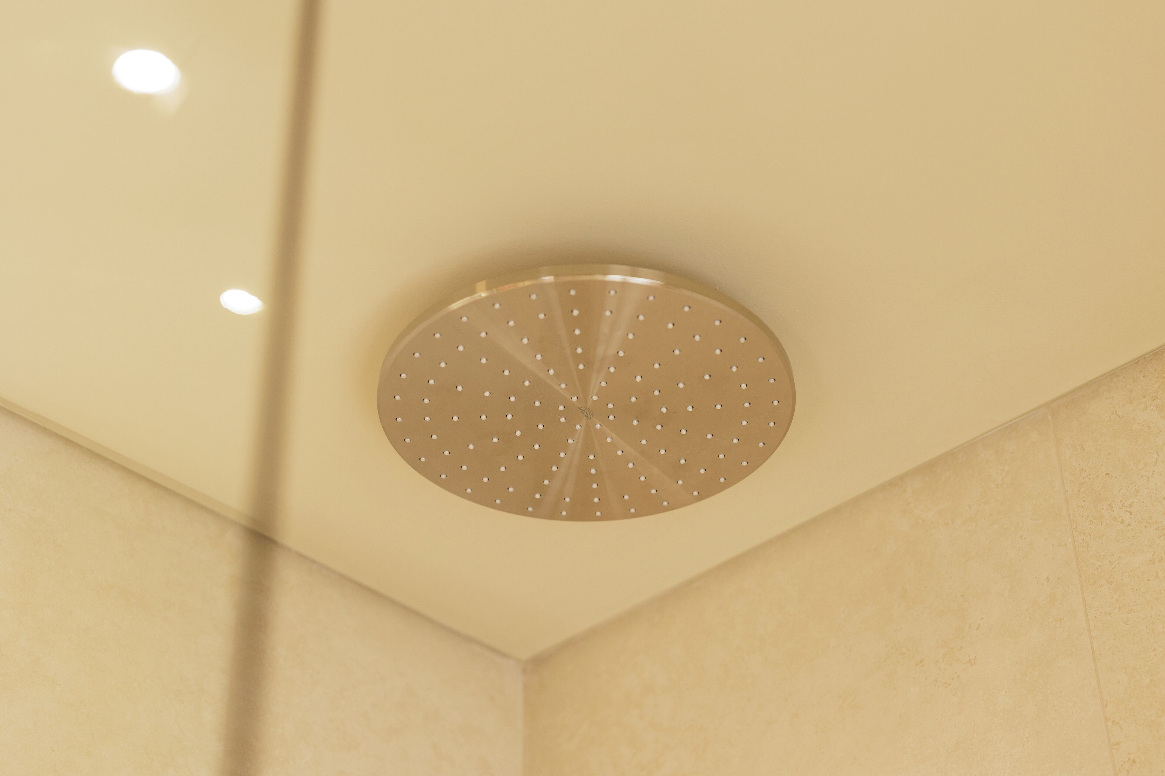 Un techo con un rociador de ducha circular en una esquina de una habitación de paredes color beige.