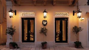 Entrada de hotel con dos puertas, cada una con un cartel arriba y luces decorativas en la pared.