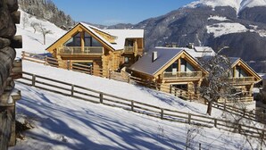 Un chalet en bois doté de balcons, situé au pied d’une montagne enneigée.