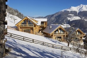 Una cabaña de madera con balcones, con una imponente montaña nevada de fondo.