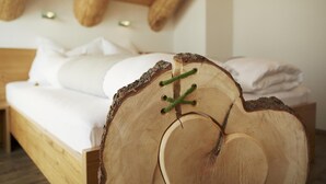 Un lit en bois dont le design est inspiré d’un tronc d’arbre, avec une literie blanche et une disposition simple de la pièce.