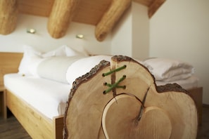 Una cama de madera con diseño de tocón de árbol, ropa de cama blanca y una distribución sencilla.