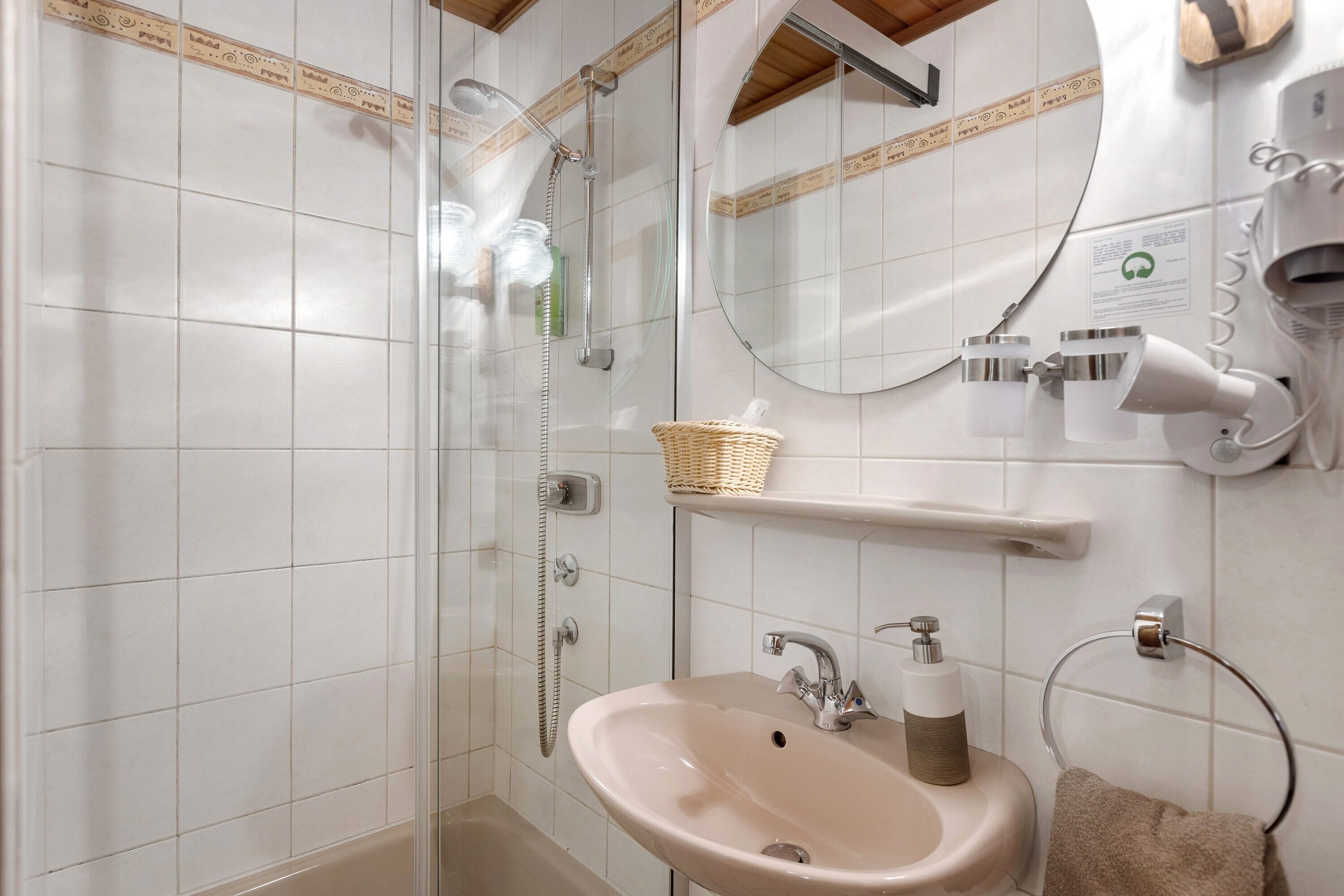Baño con ducha, lavabo, toallero y espejo.