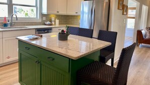 A kitchen with a green island, stainless steel appliances, wicker chairs, and pendant lighting. - Coastal Fave- Lrg Private Pool + 2 Min Beach Walk (Santa Rosa Beach)