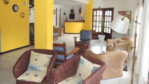 A room with wicker furniture, yellow walls, and a large window. - Casablanca (Villa Gesell)