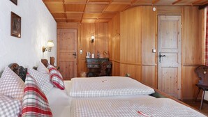 Quarto com painéis de madeira, duas camas, uma escrivaninha de madeira e uma porta.