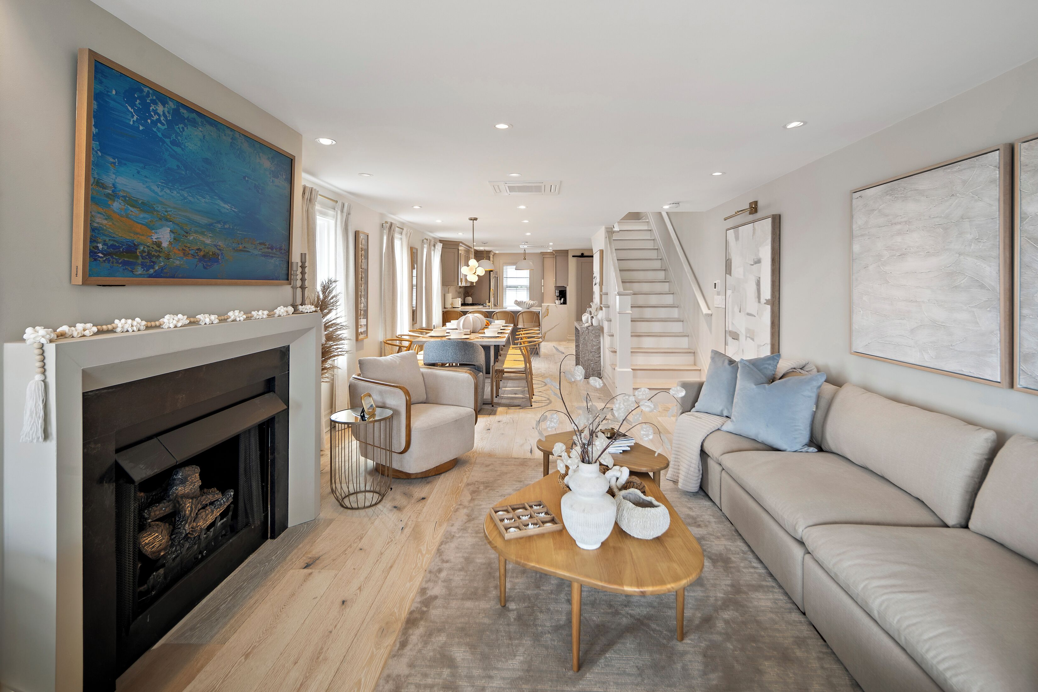 A spacious living room with a fireplace, a sofa, a coffee table, and a dining area in the background.
