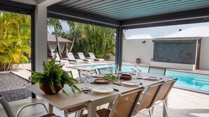 A poolside dining area with a table set for four, overlooking a pool and palm trees. - Villa La Rosière, luxury 4-suite villa, private pool & jacuzzi (STE ANNE)
