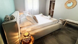 A modern bedroom with a bed, bedside table, lamp, and a mirror on the wall. - Villa La Rosière, luxury 4-suite villa, private pool & jacuzzi (STE ANNE)