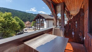 A wooden balcony with a view of a mountain and a building with a sloped roof. - Standard Double Room with Shared Garden, Balcony and Wi-Fi (Schramberg)