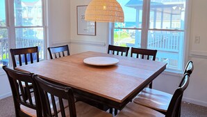 A dining area with a wooden table and chairs, a woven pendant light, and a framed picture on the wall. - Amazing ocean views, Sleeps 8, Beach access, Pets OK (Surf City)
