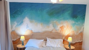 A bedroom with a large wall mural of a wave, two bedside tables with lamps, and a bed with white bedding. - Amazing ocean views, Sleeps 8, Beach access, Pets OK (Surf City)