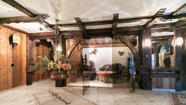 A rustic interior with wooden walls, a large mirror, and a stone floor. - Large Double Room with Shared Garden, Balcony and Wi-Fi (Schramberg)