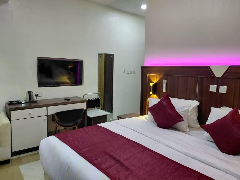 A hotel room with a bed, desk, chair, and a television mounted on the wall.