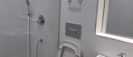 A bathroom with a toilet, bidet, shower, and sink.