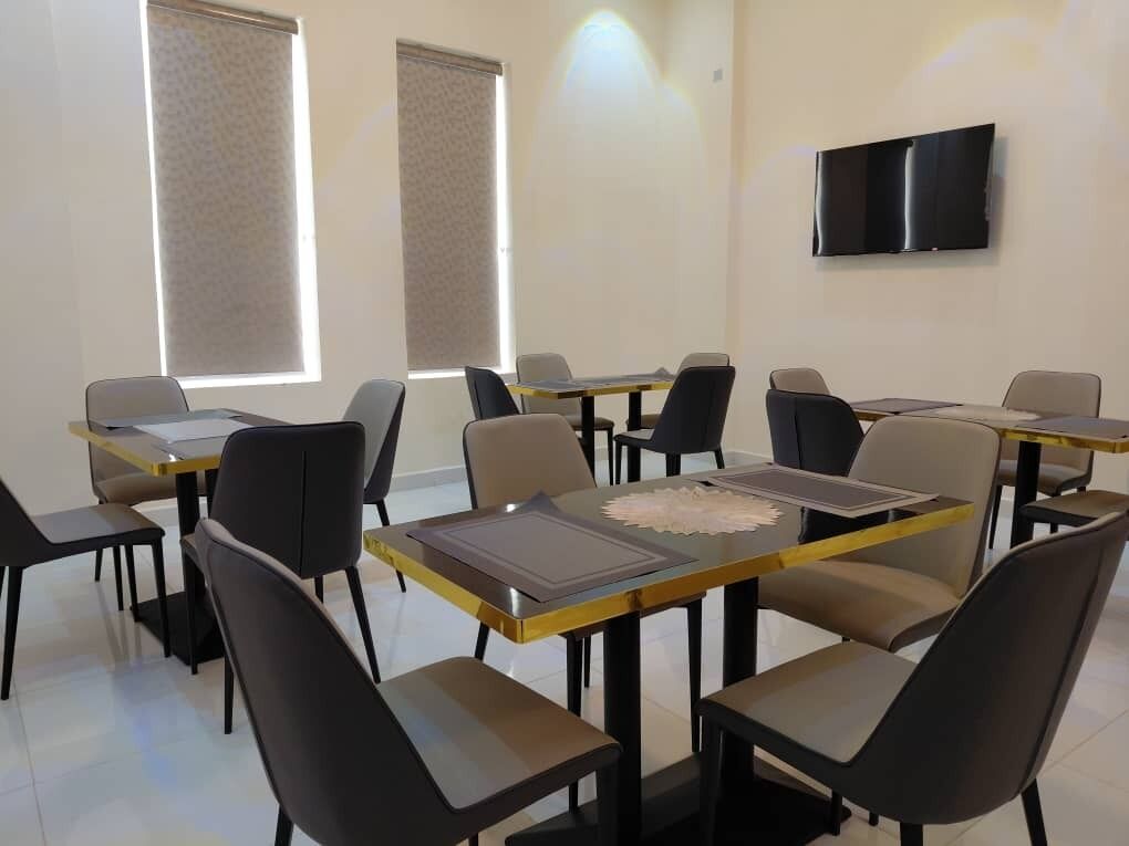 Une salle de conférence équipée de plusieurs tables et chaises, d’un téléviseur à écran plat fixé au mur et de grandes fenêtres dotées de stores.