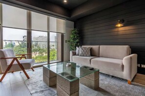 A modern living room with a glass coffee table, a sofa, and a chair.