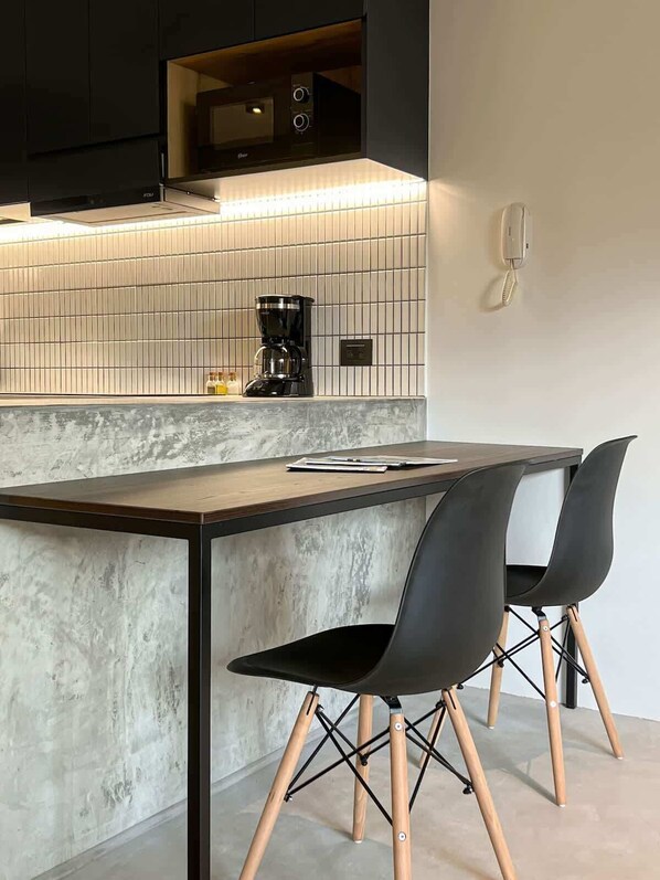 A modern kitchen with a tiled backsplash, a coffee maker, and a telephone.