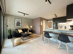A modern living room with a sofa, coffee table, and a dining area with chairs.