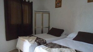 Una habitació amb dos llits, un armari i un quadre a la paret.